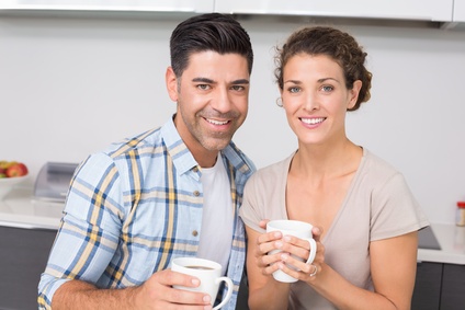 Happy couple having coffee smiling at camera